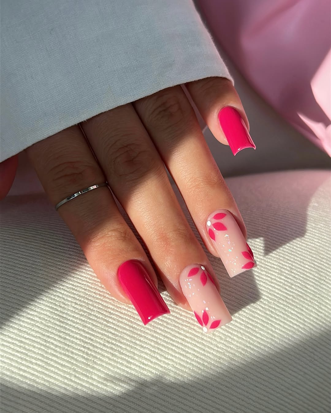 Vibrant pink nails with floral accents
