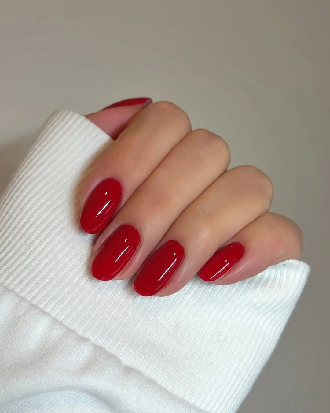 Glossy red nails peek from cozy attire