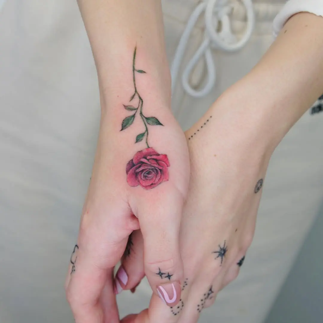 Delicate rose tattoo adding charm to hands
