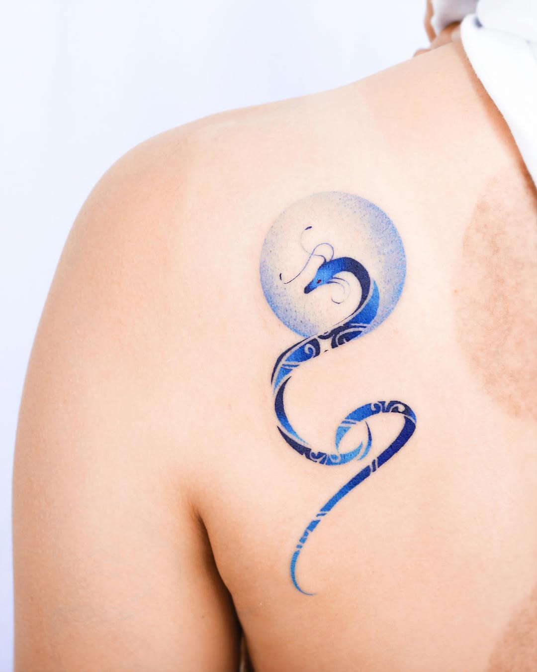 Elegant snake tattoo wrapped around moon