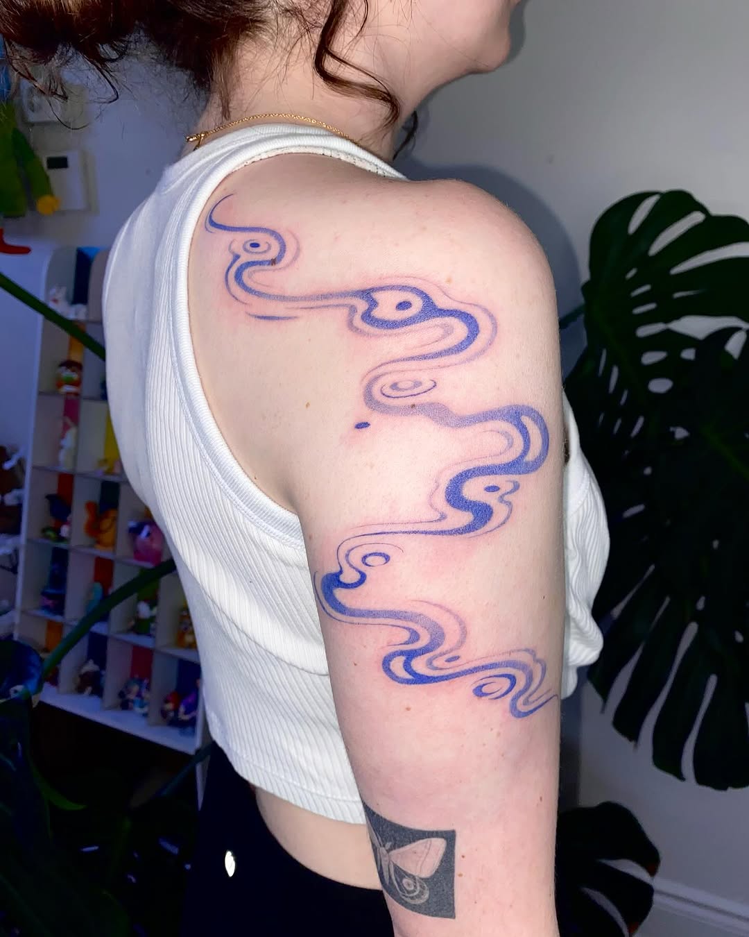 Flowing blue wave design on shoulder tattoo
