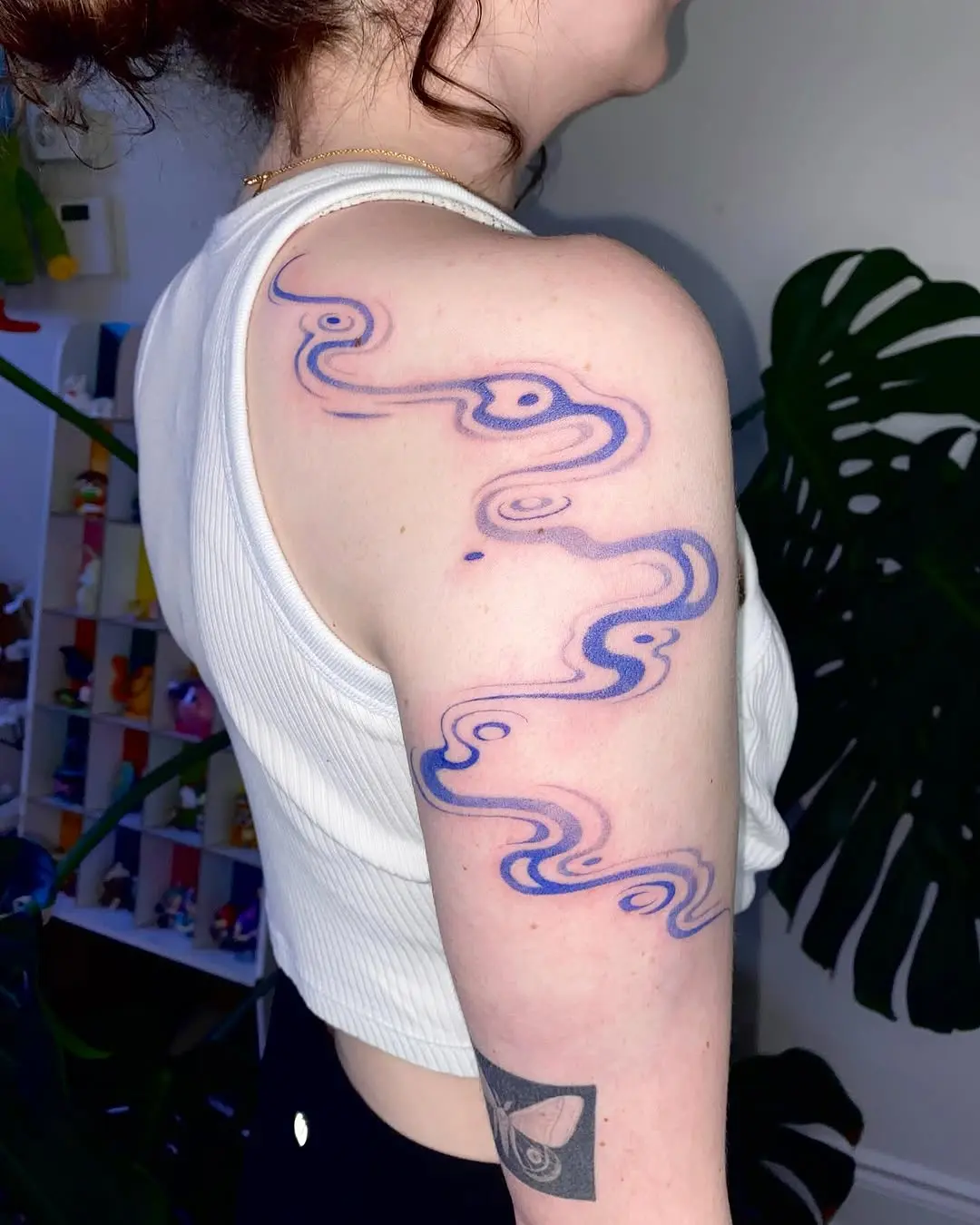 Flowing blue wave design on shoulder tattoo