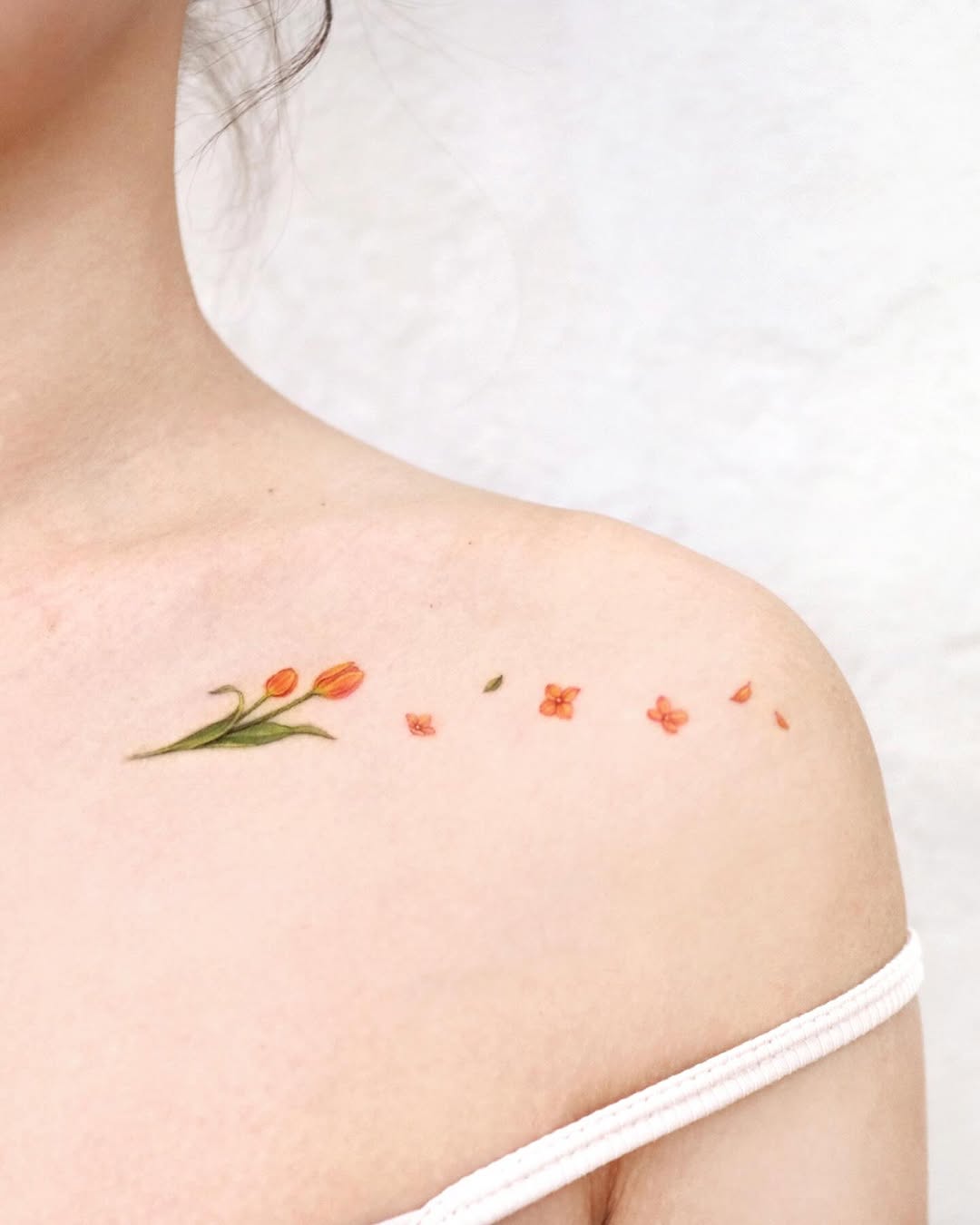 Delicate orange floral shoulder tattoo design