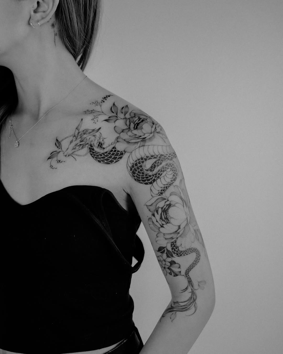 Intricate shoulder tattoo featuring a snake and flowers