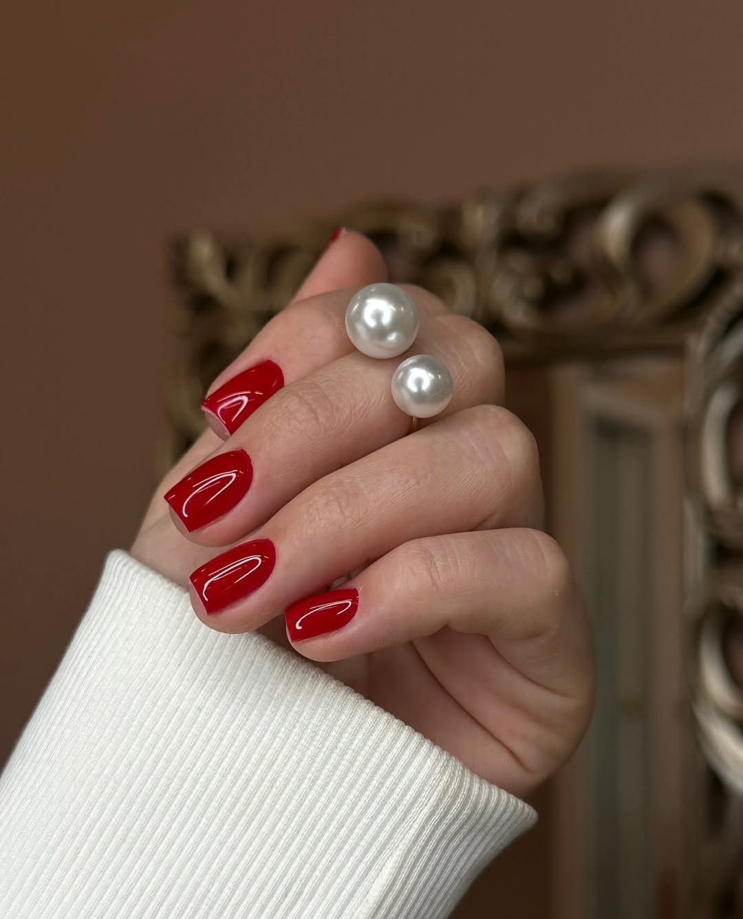 Bold red nails paired with elegant pearls