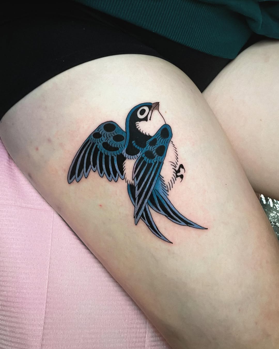 Bold blue swallow flying on thigh tattoo