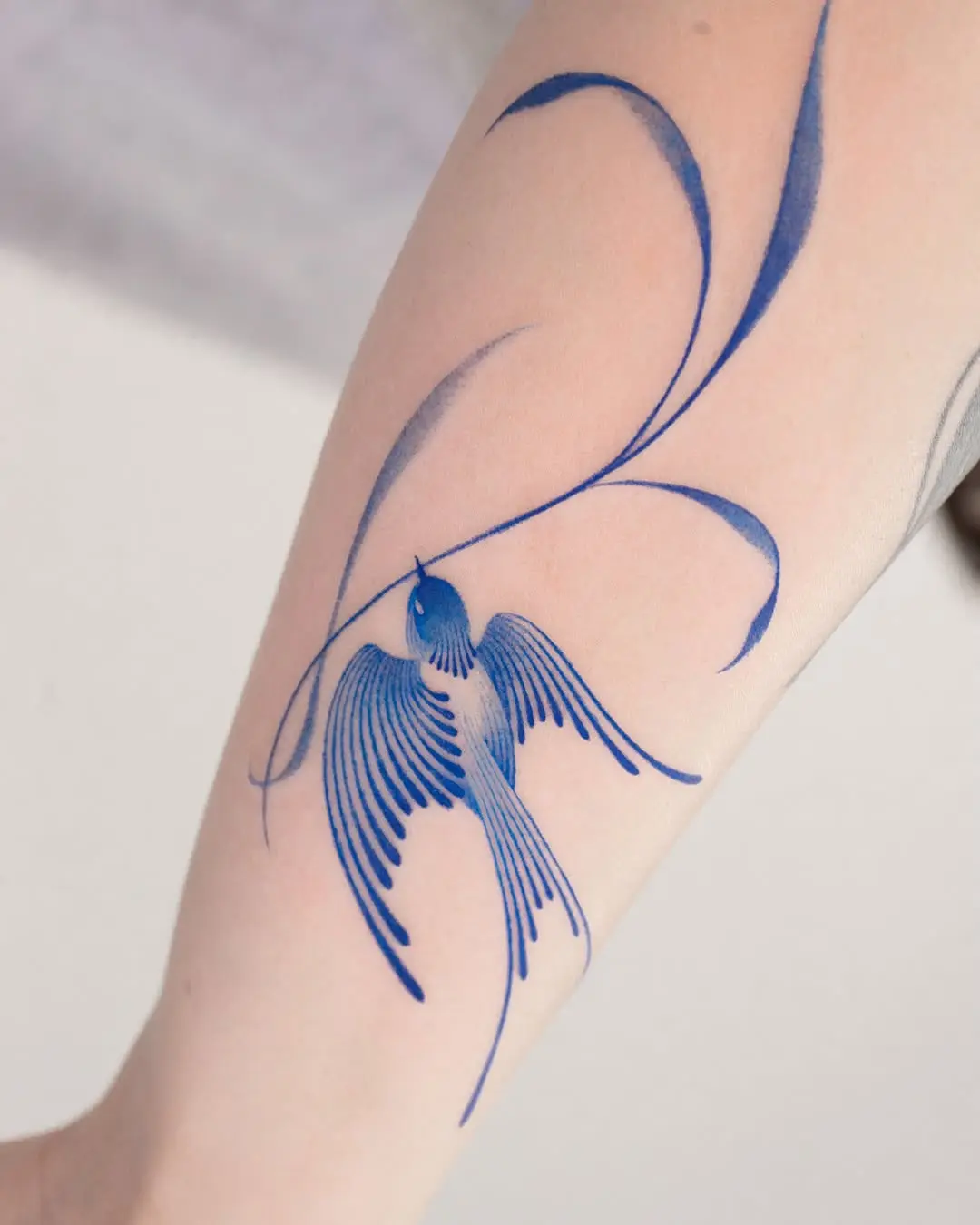 Elegant blue swallow tattoo with flowing lines