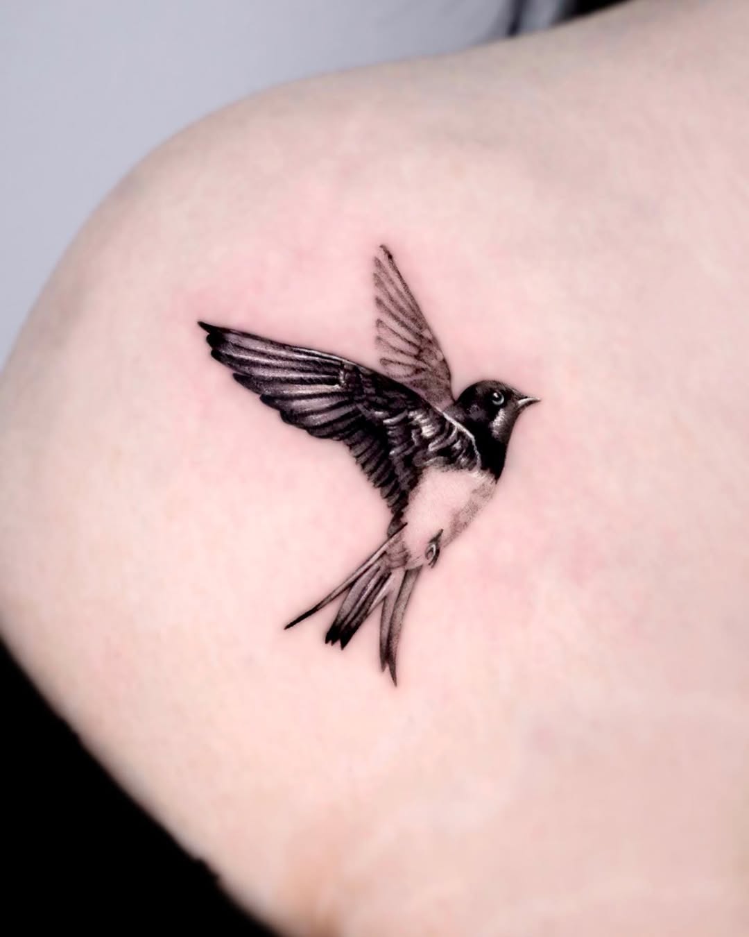 Elegant swallow tattoo in flight captures freedom.