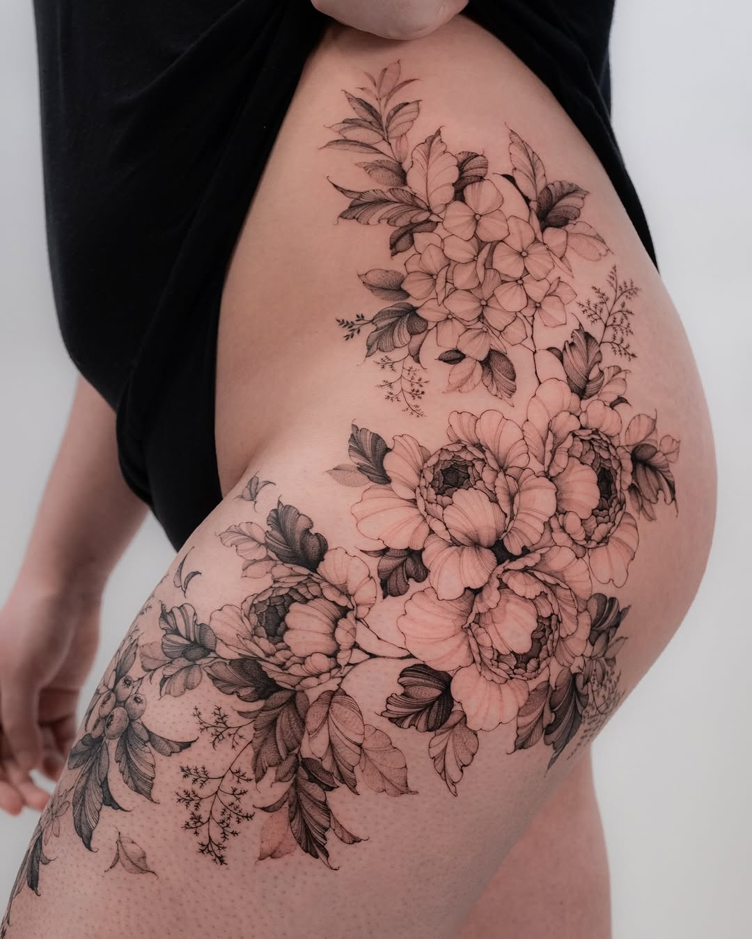 Elegant floral thigh tattoo showcasing stunning peonies