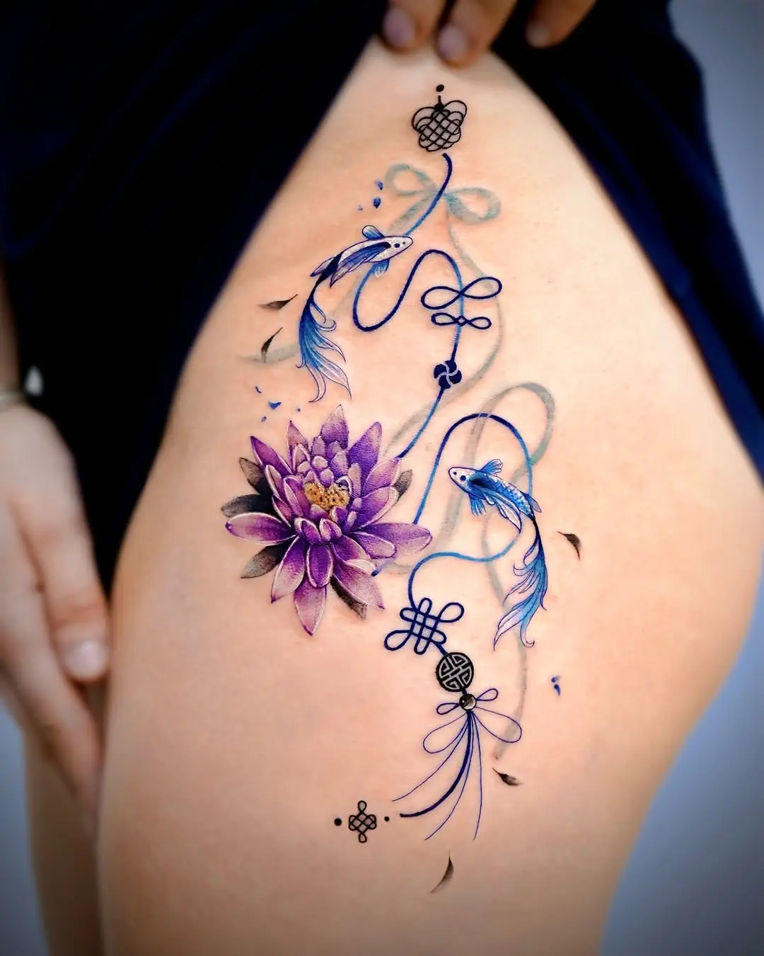 Stunning lotus and fish thigh tattoo design