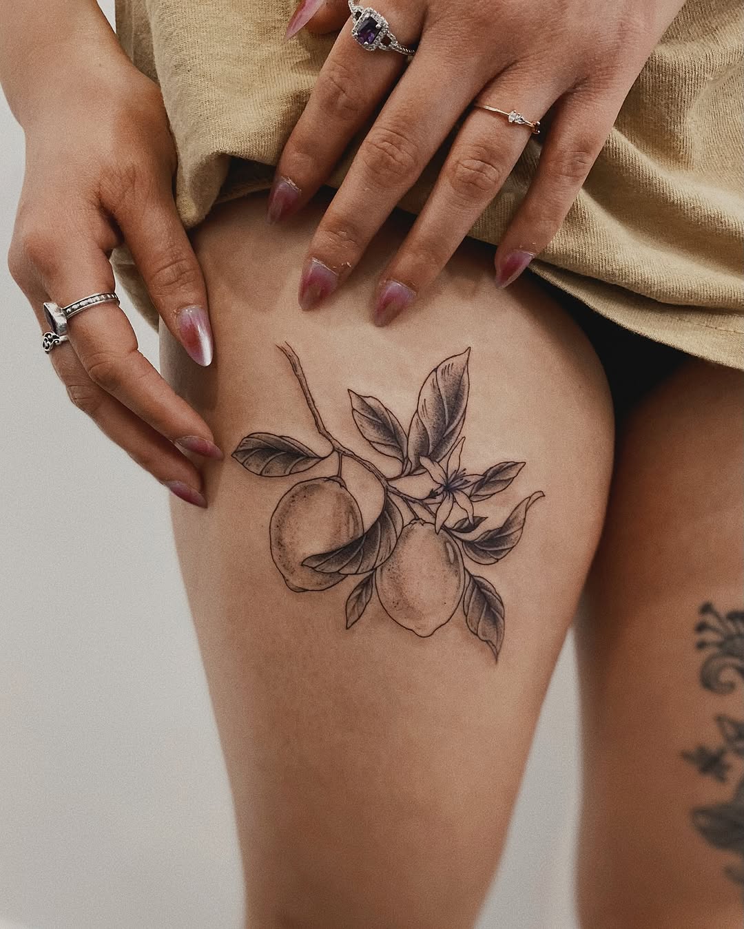 Elegant thigh tattoo of lemons and leaves