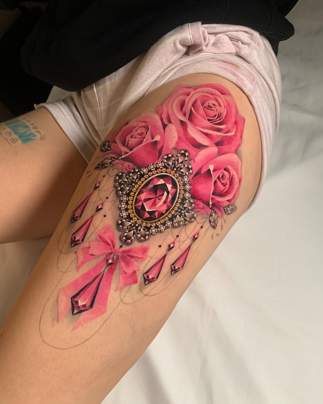 Stunning thigh tattoo of roses and jewels