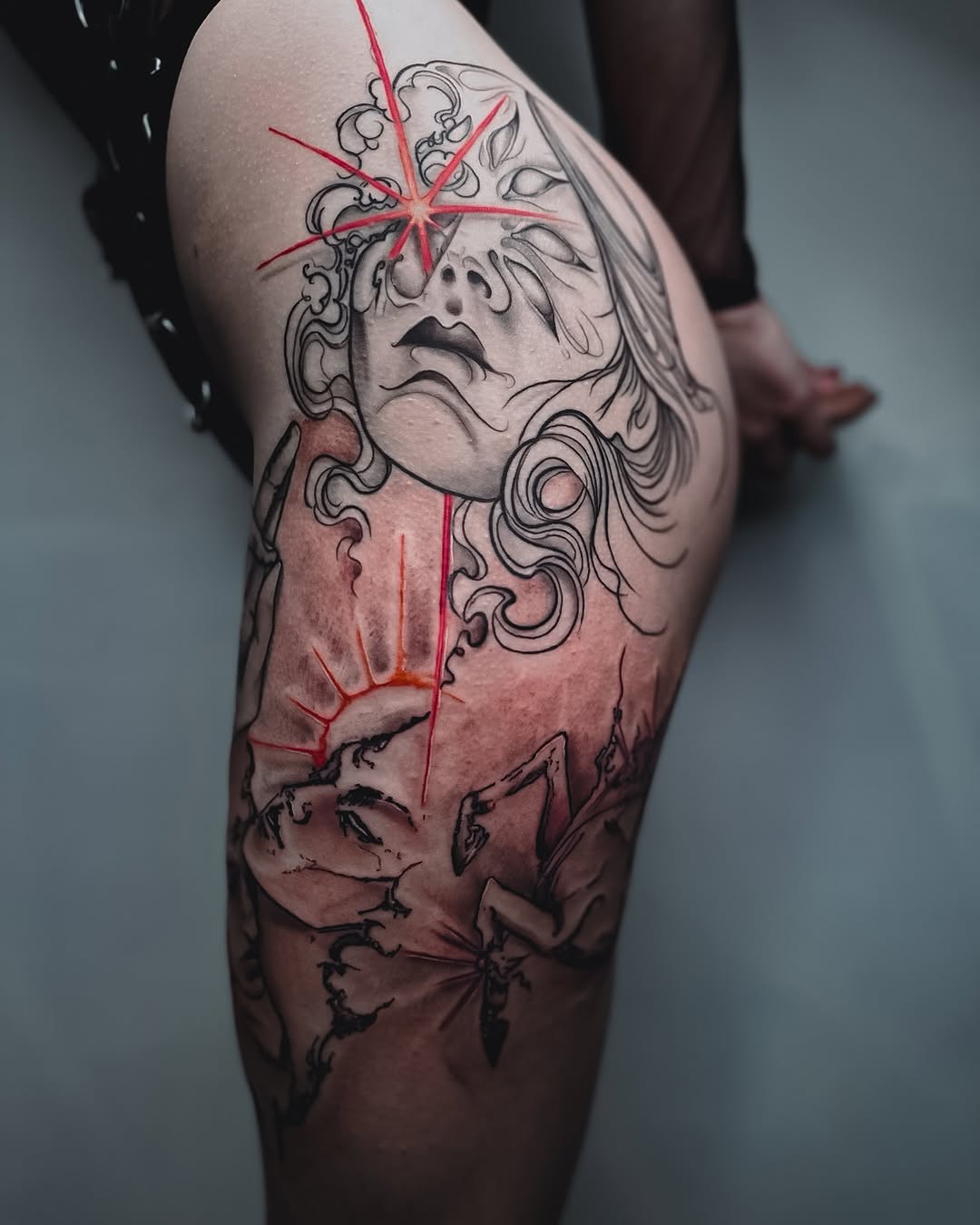 Striking thigh tattoo with dramatic facial imagery