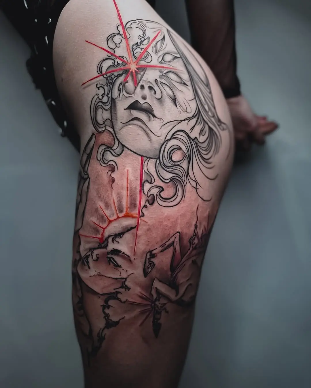 Striking thigh tattoo with dramatic facial imagery