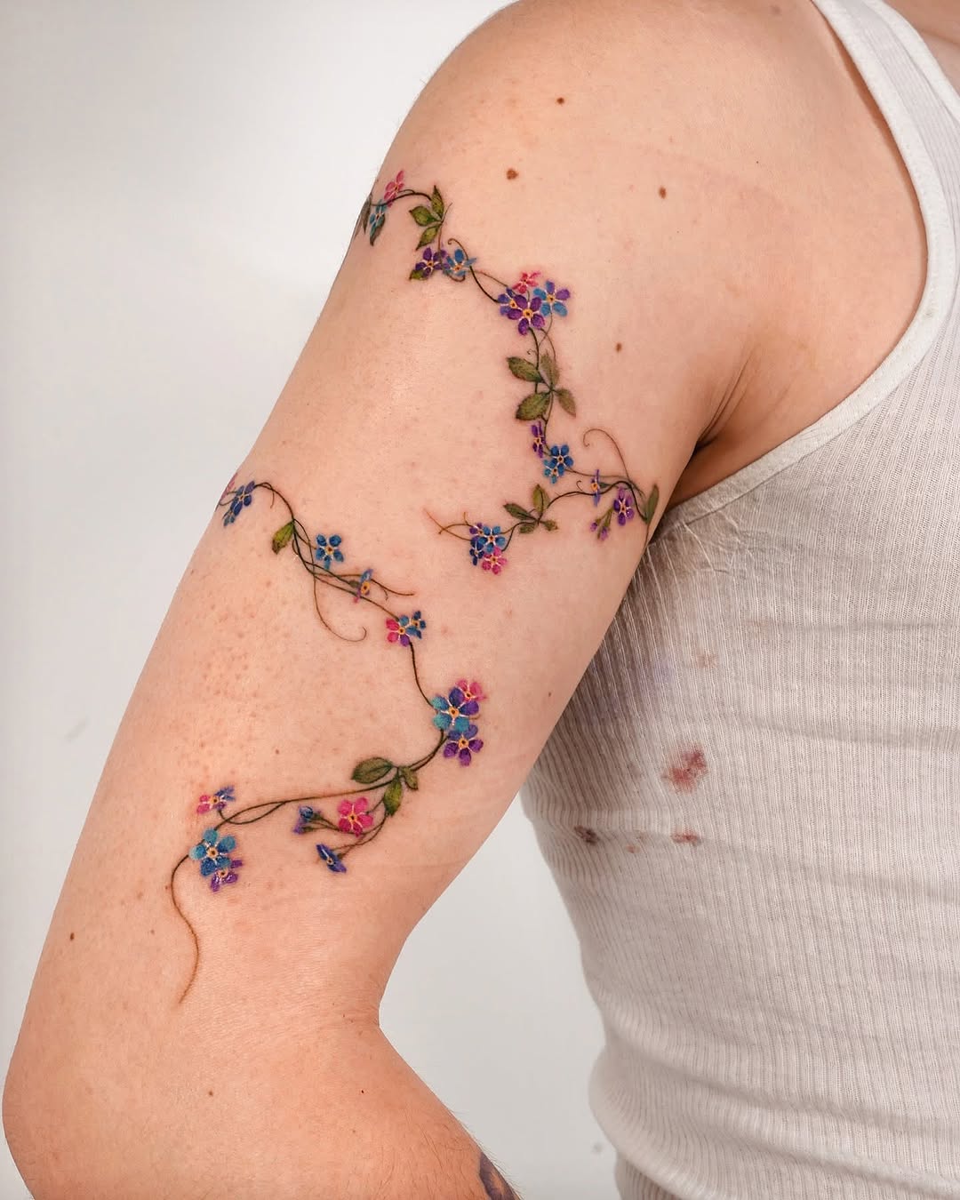Colorful floral tattoo winding up the arm