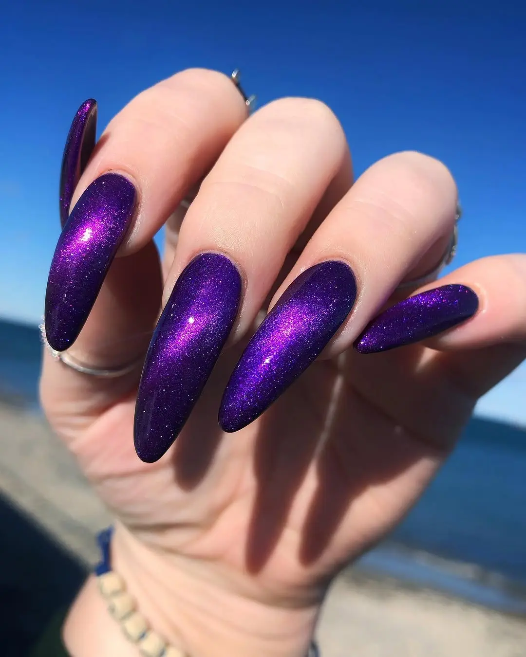 Glamorous glittery purple stiletto nails shine brightly