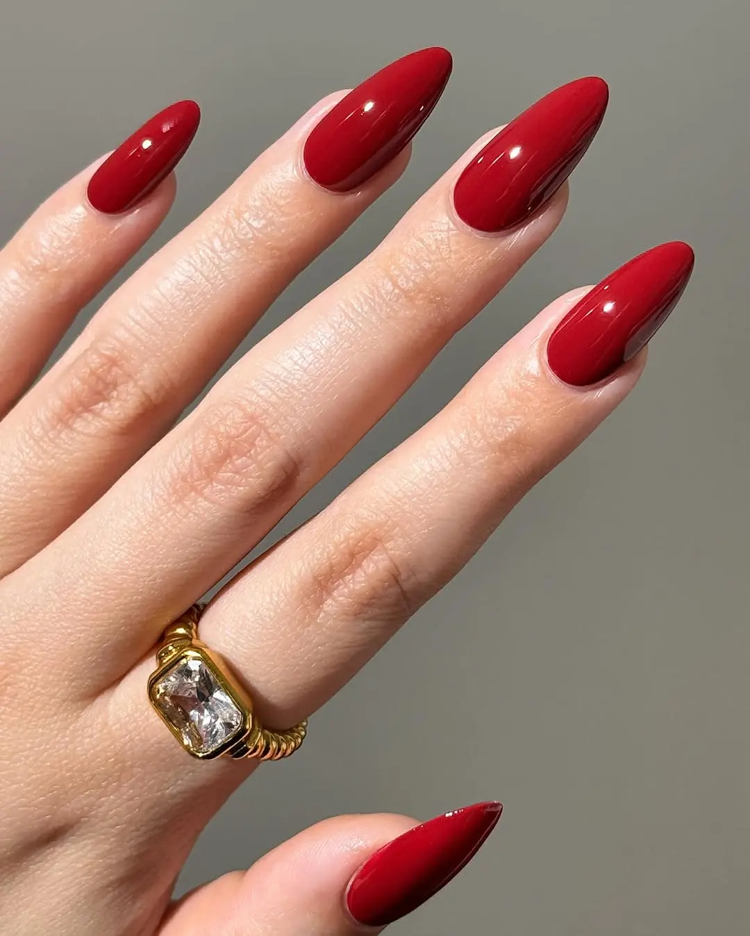 Sleek pointed red nails with golden ring