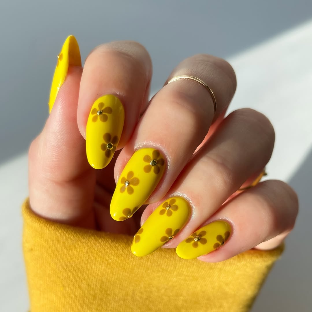 Bright yellow nails adorned with floral designs
