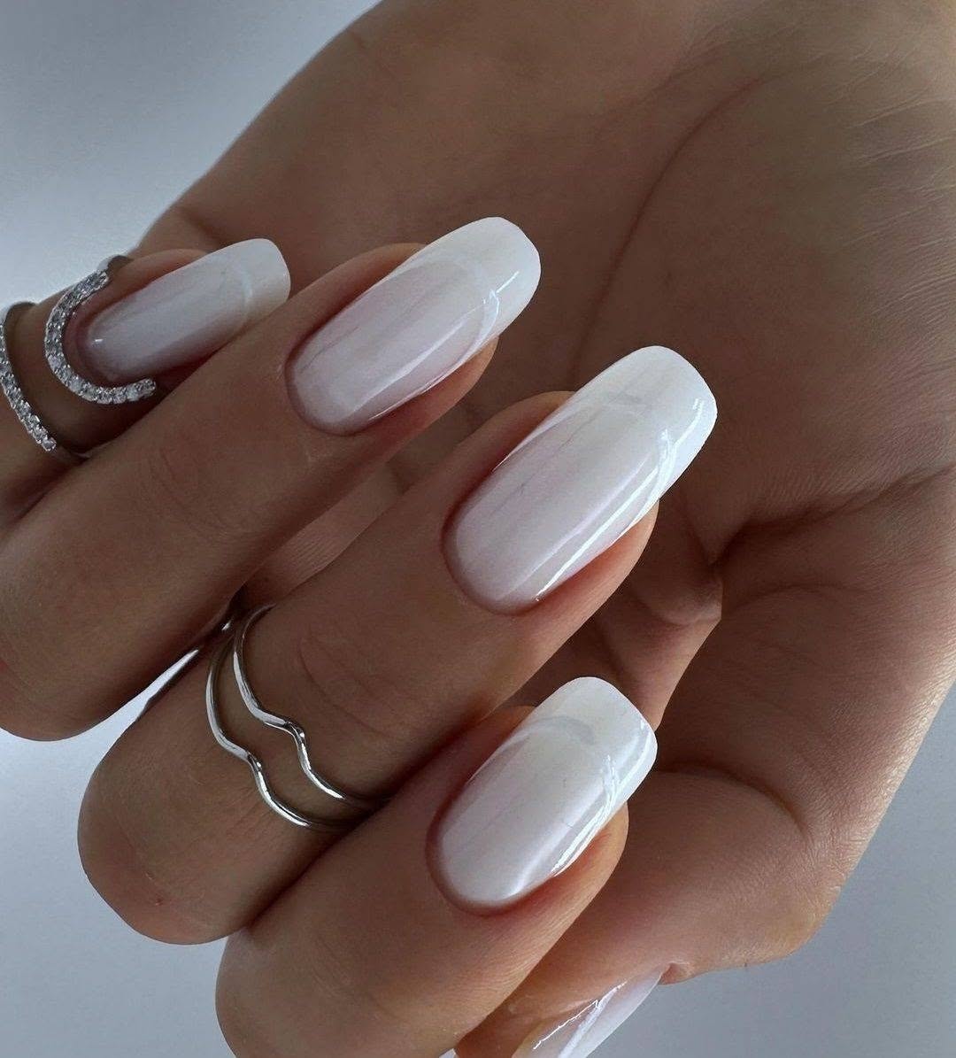 Sleek white nails adorned with delicate rings