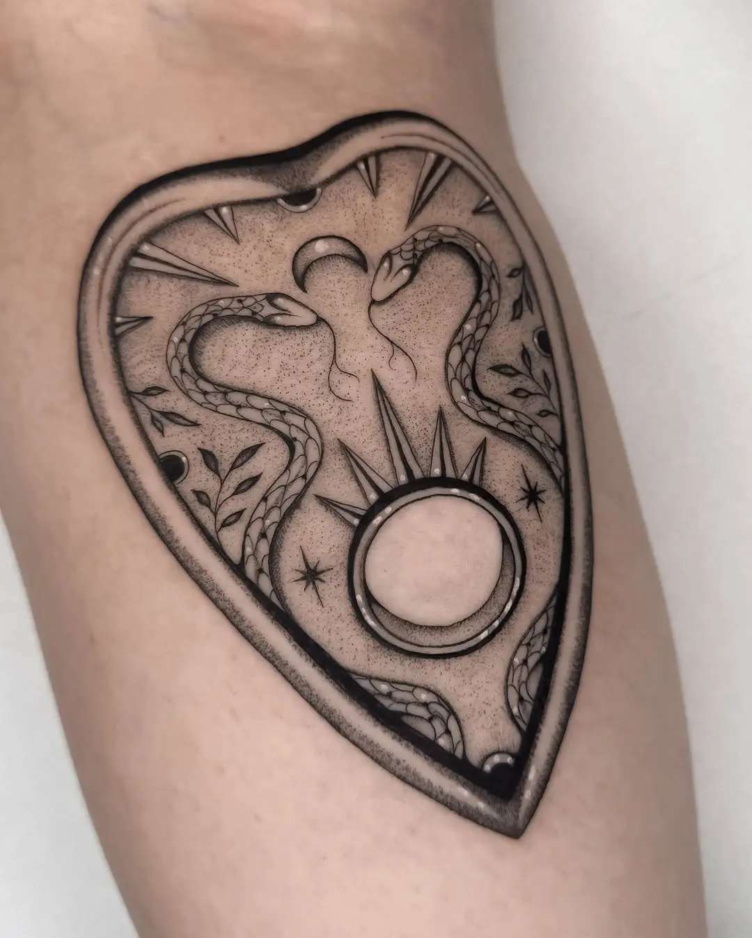 Snakes and moon in a shield tattoo design