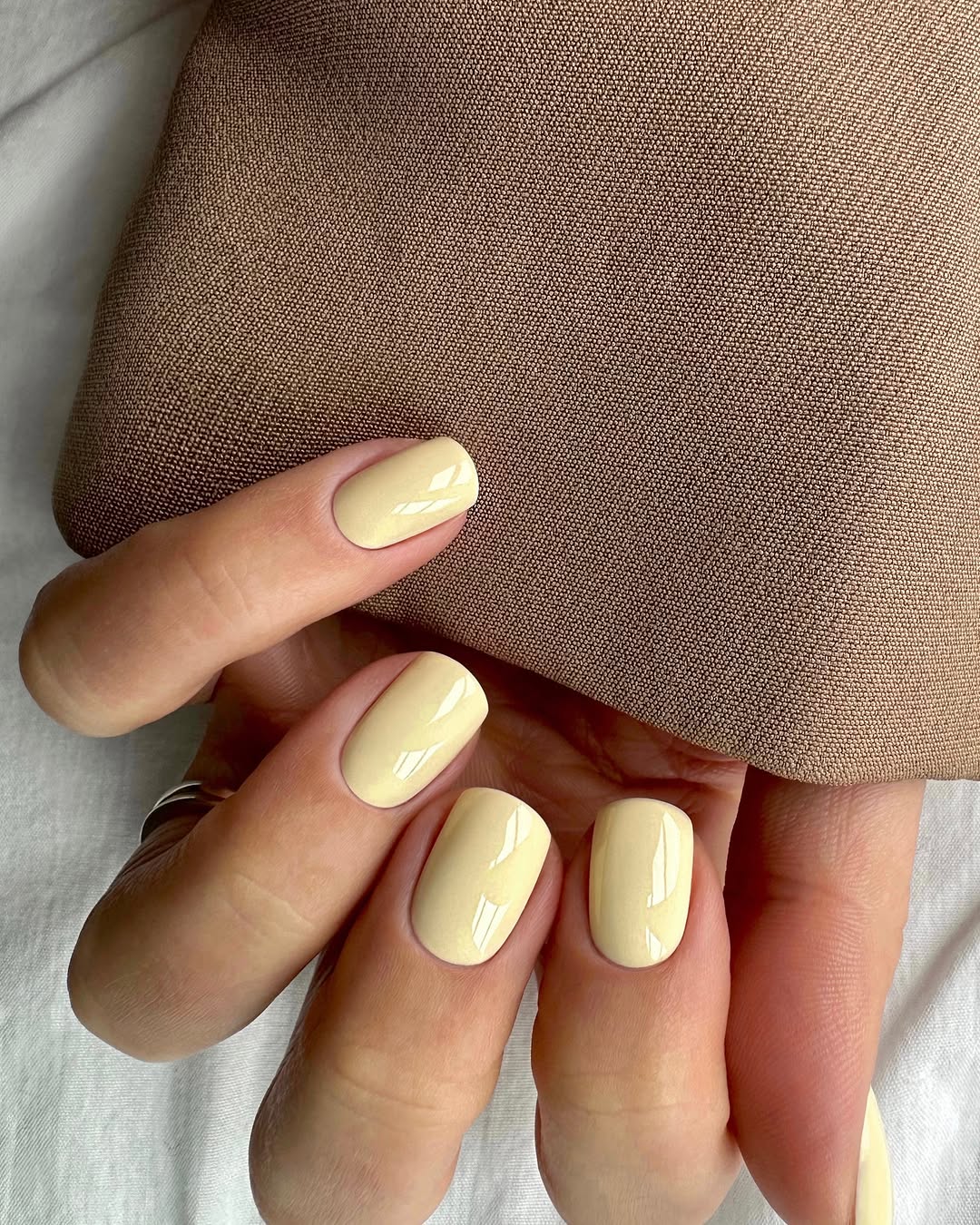 Glossy yellow nails with chic fabric background