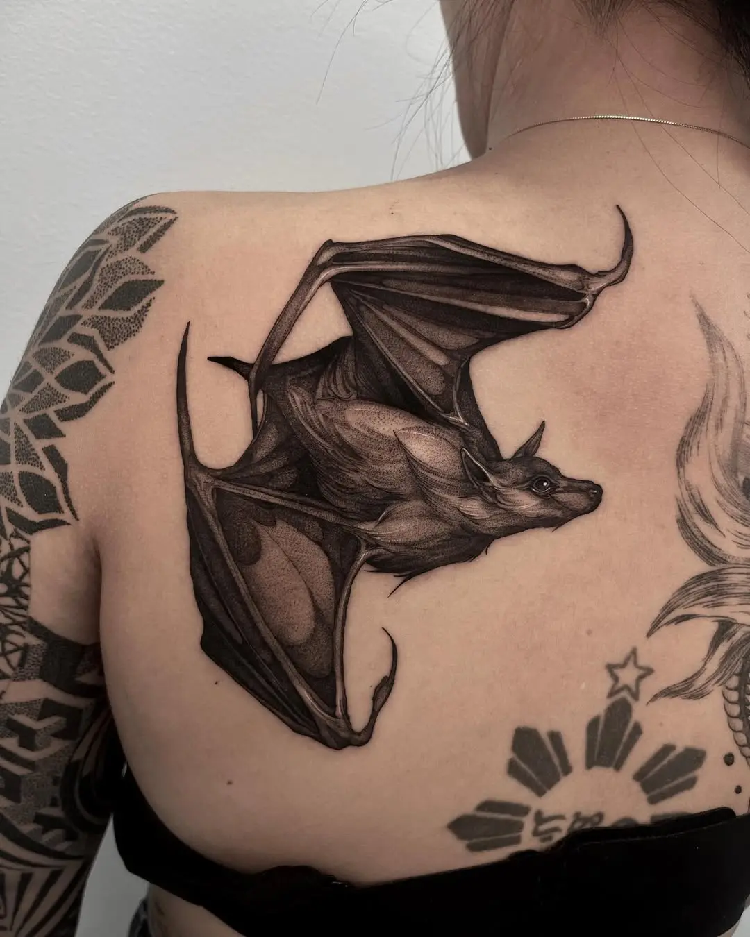Intricate flying bat tattoo on back