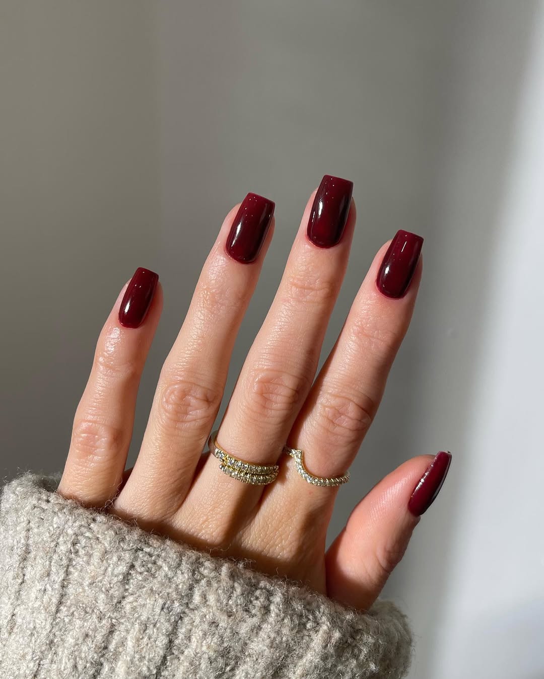 Glossy burgundy nails with elegant rings