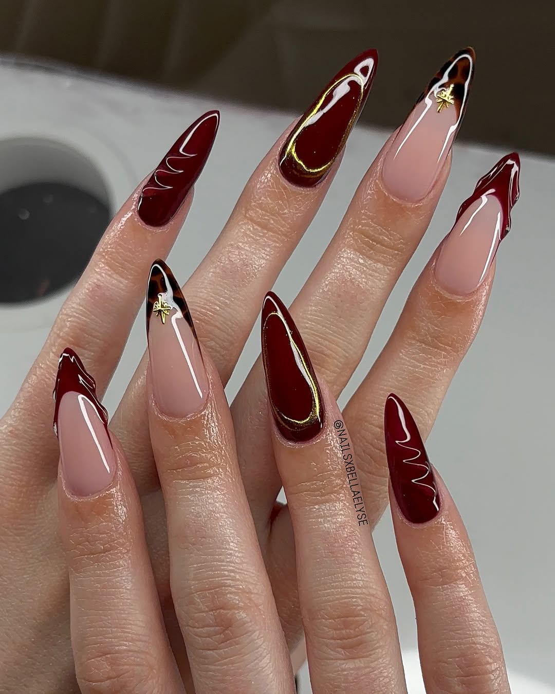 Stylish burgundy stiletto nails with gold accents
