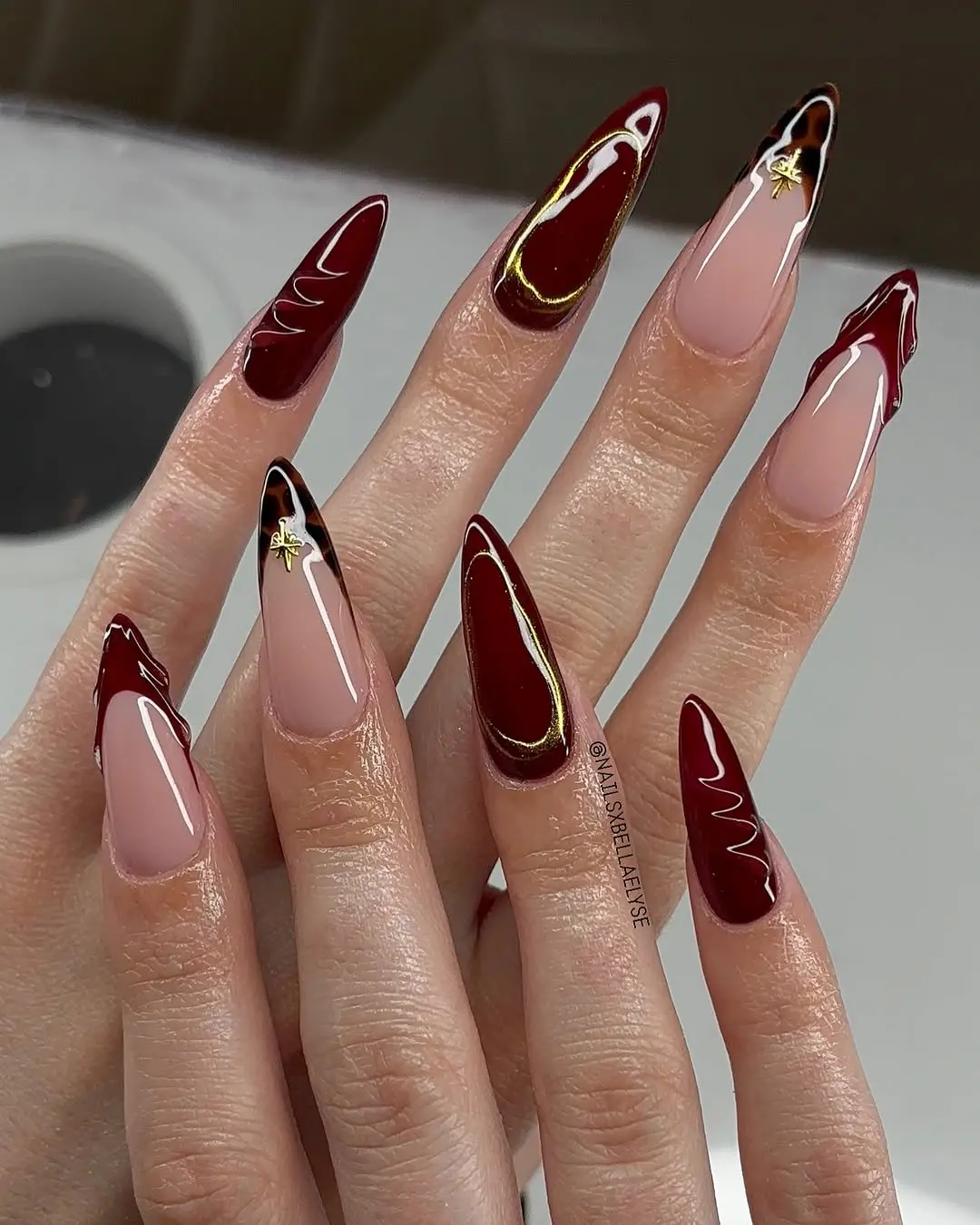 Stylish burgundy stiletto nails with gold accents