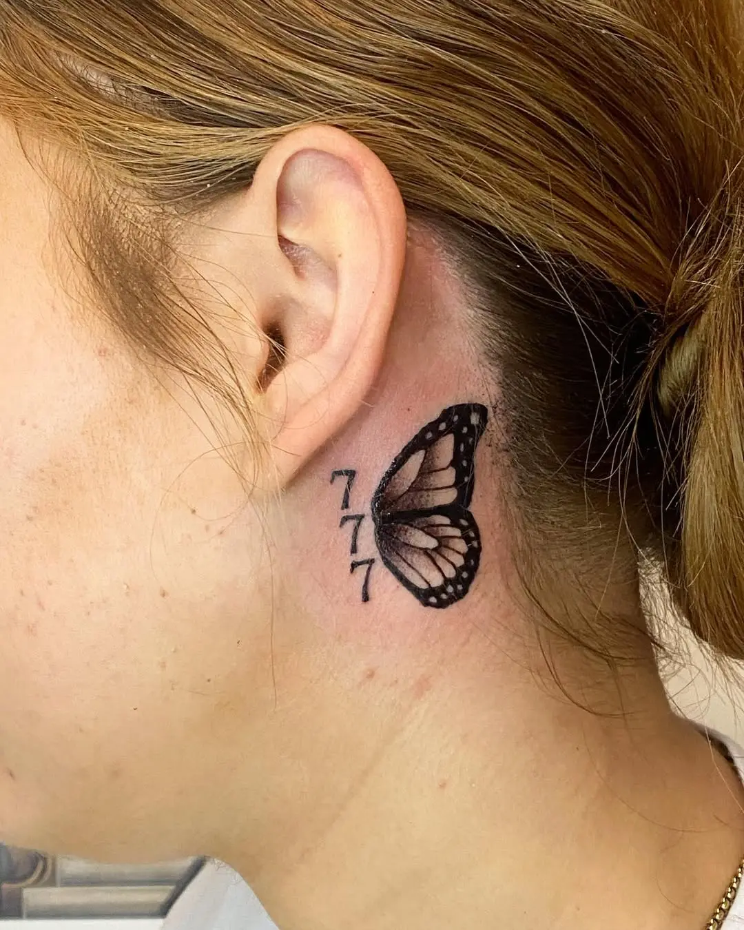 Symbolic butterfly inked near the ear