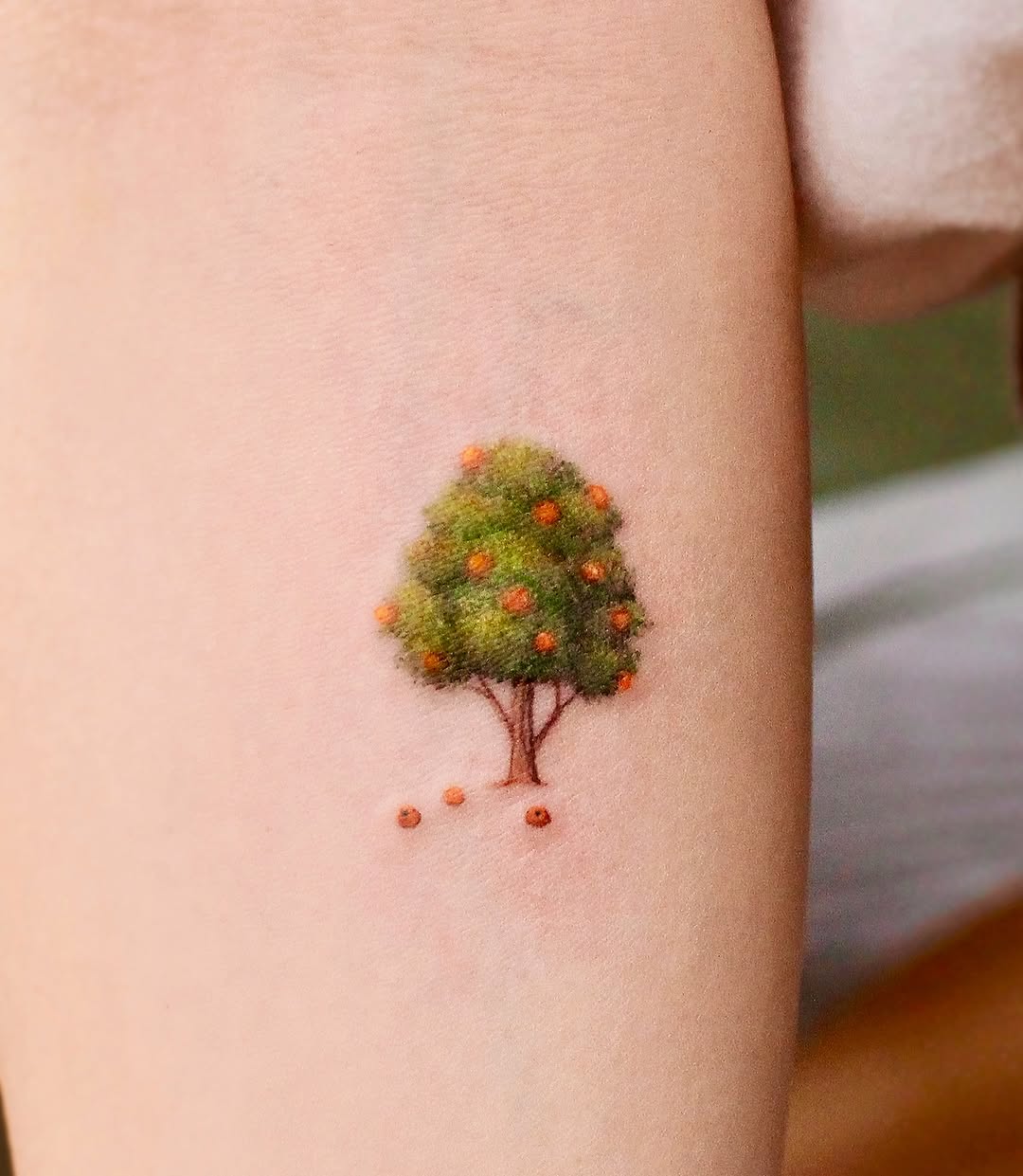 Whimsical orange tree tattoo on the arm