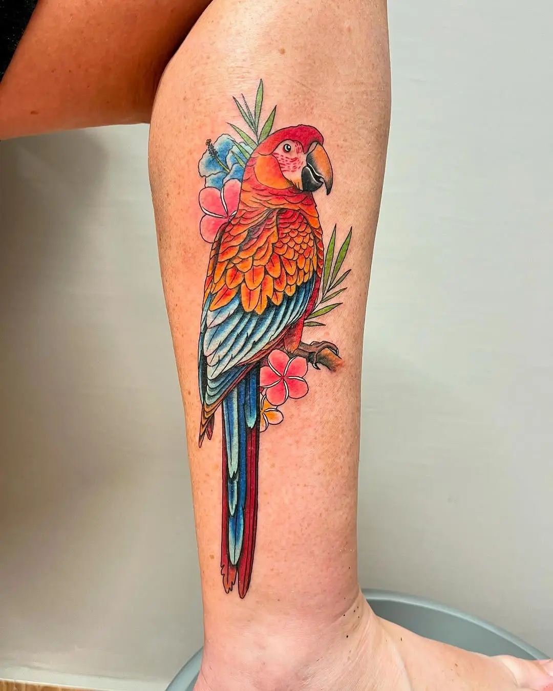Vibrant parrot tattoo with floral accents