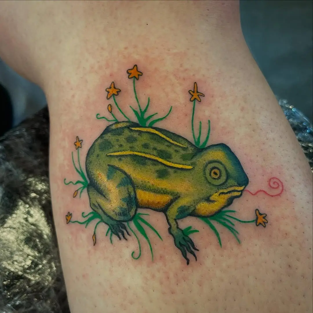 Vibrant frog tattoo surrounded by wildflowers