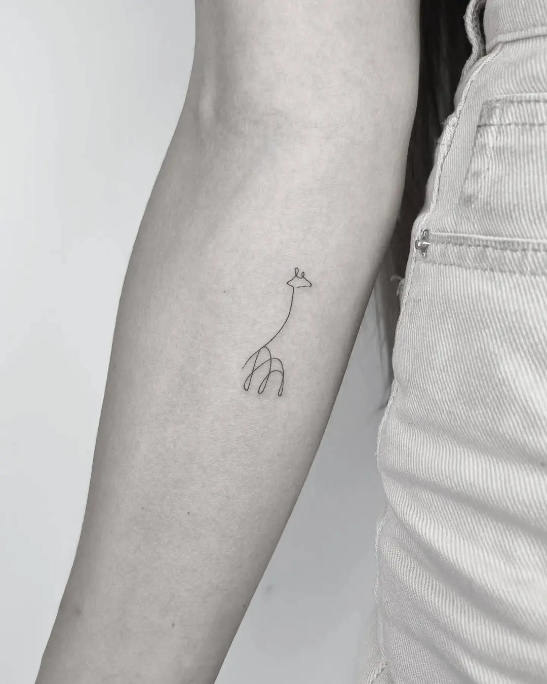 Charming minimalist giraffe one-line tattoo