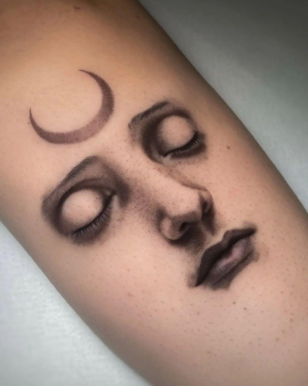 Serene face tattoo with crescent moon detail