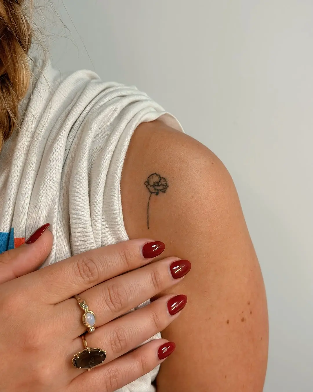 Delicate minimalist flower tattoo on shoulder