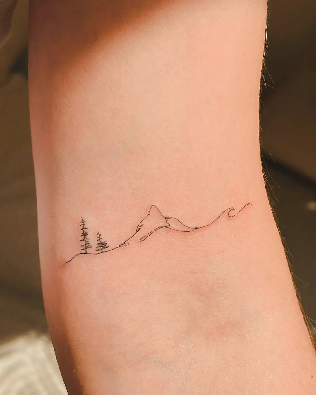 Delicate mountain and wave minimalist tattoo