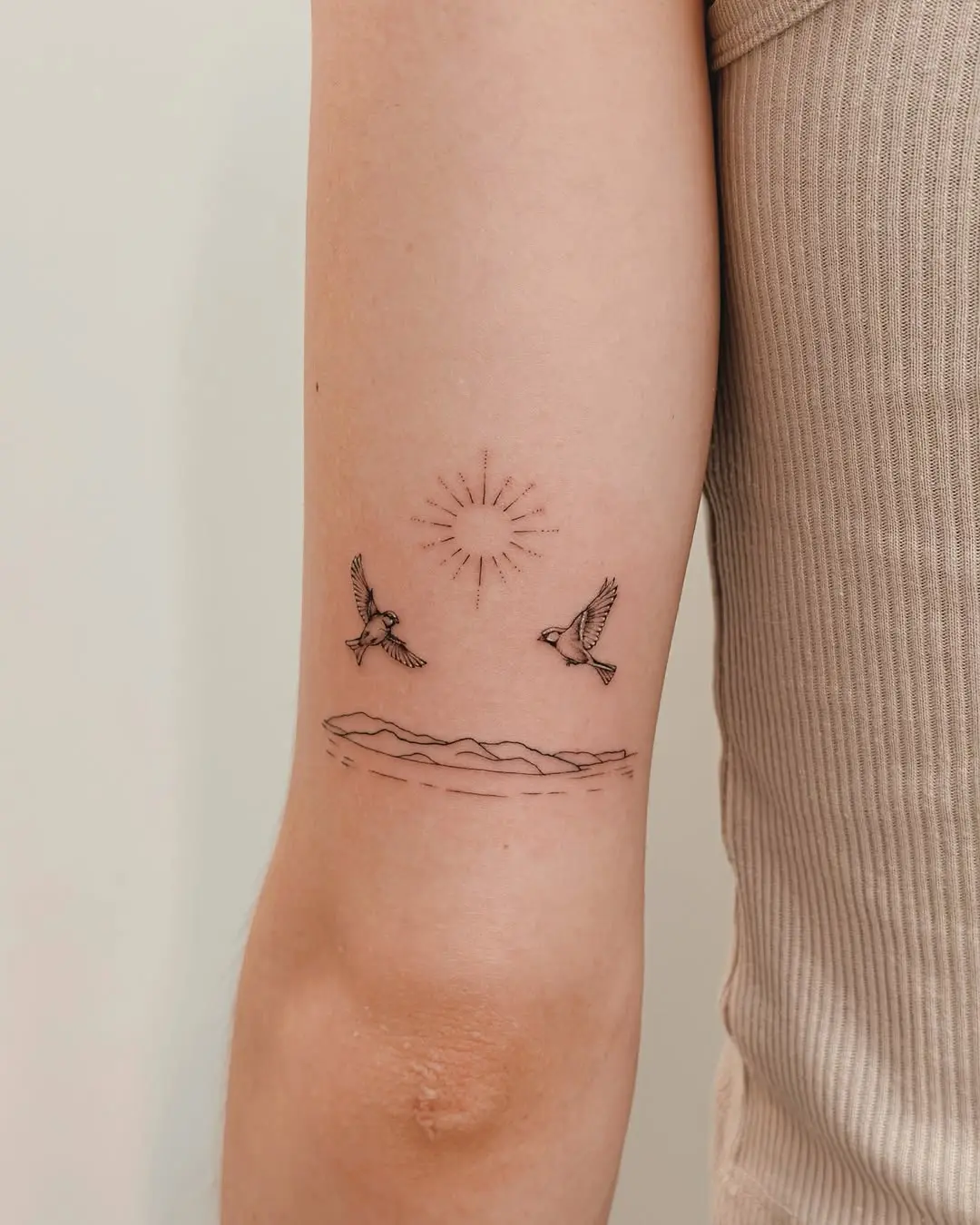 Charming minimalist tattoo of birds and sun