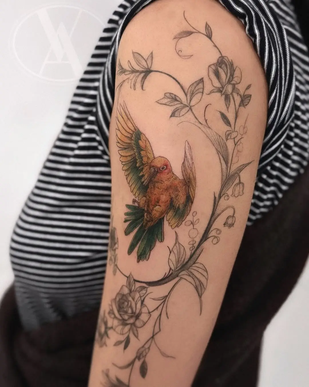 Colorful parrot tattoo with floral embellishments