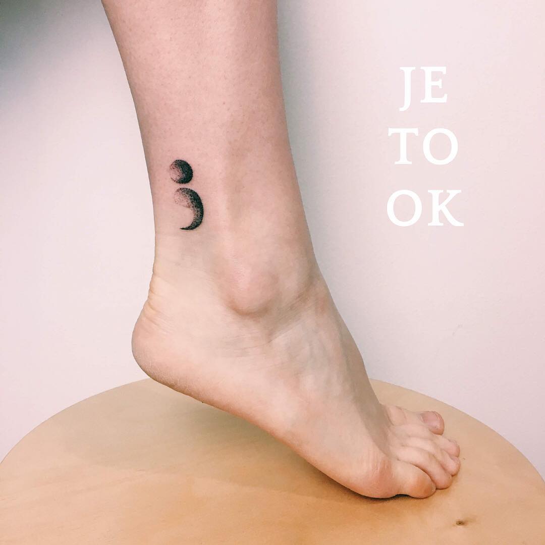 Minimalist semicolon tattoo on the ankle