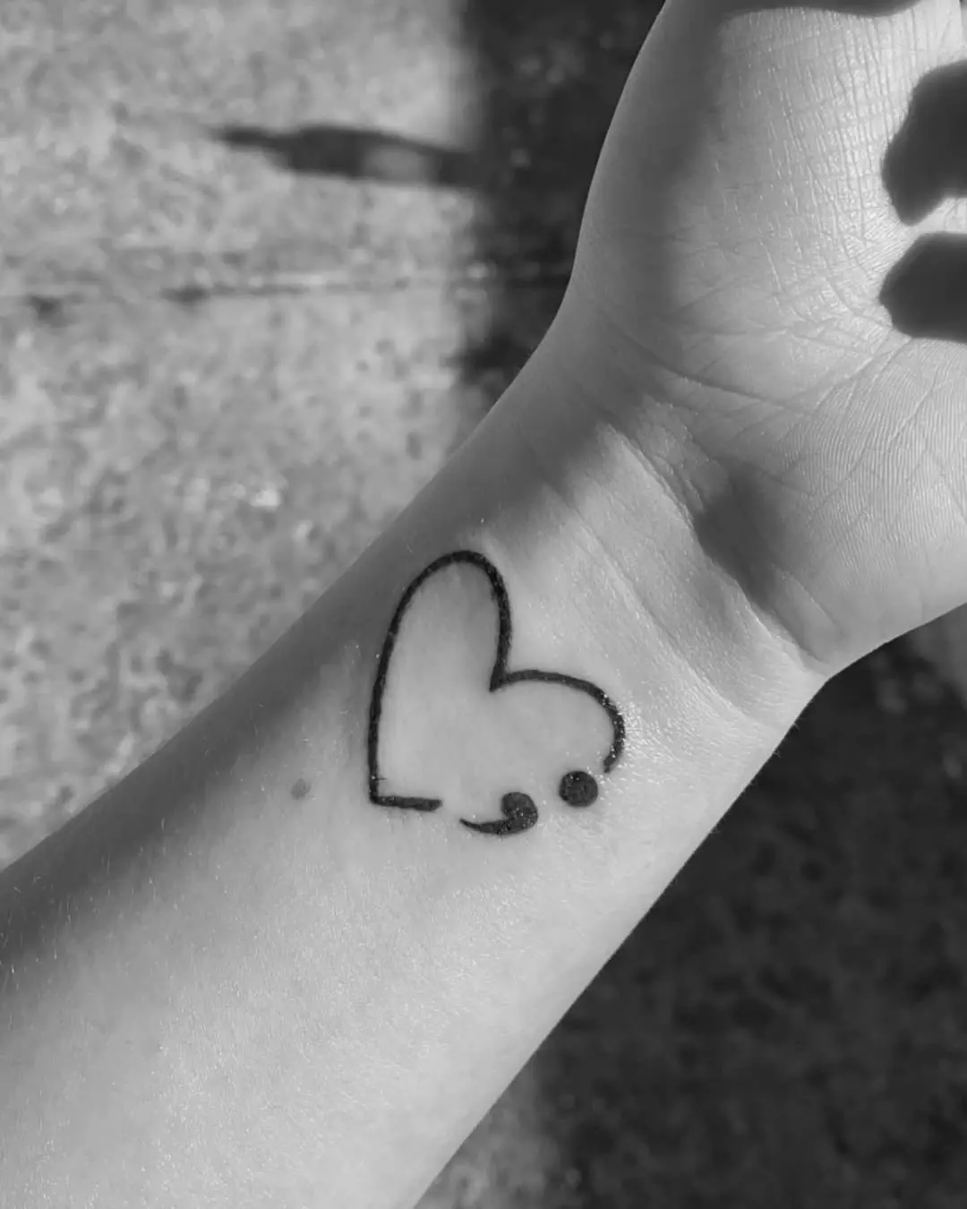 Heart-shaped semicolon tattoo on wrist