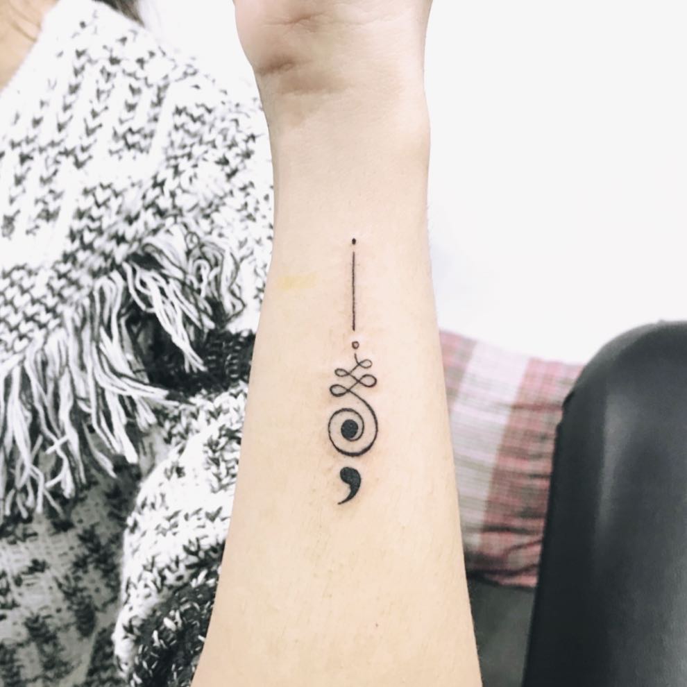 Elegant minimalist semicolon tattoo on forearm