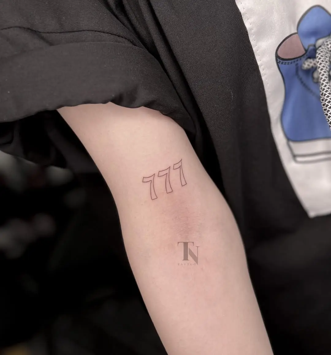 Minimalist red 777 tattoo with clean lines.