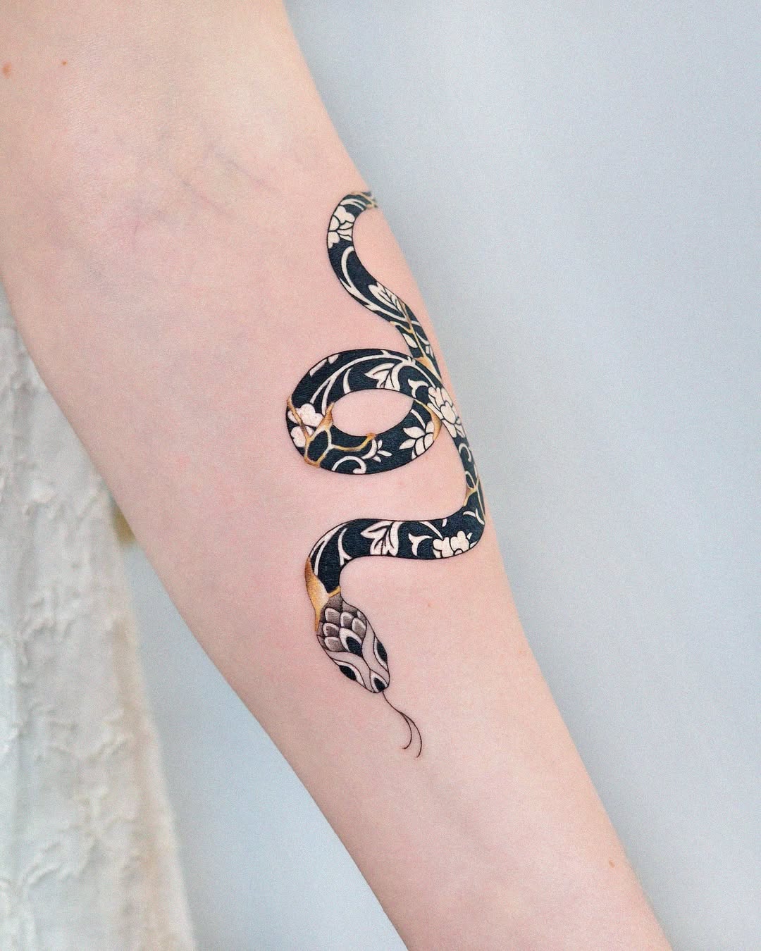 Intricate snake tattoo with floral kintsugi design