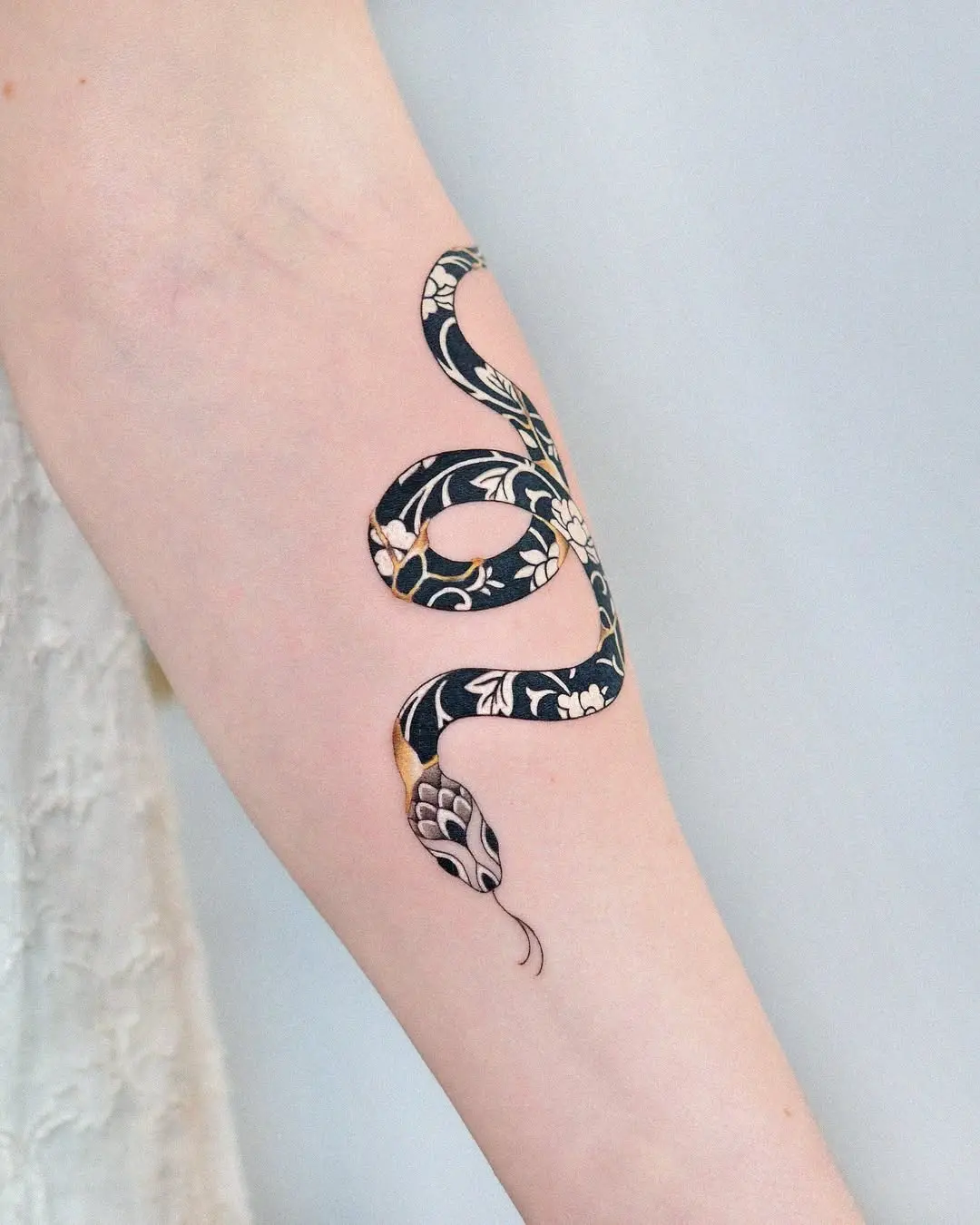Intricate snake tattoo with floral kintsugi design