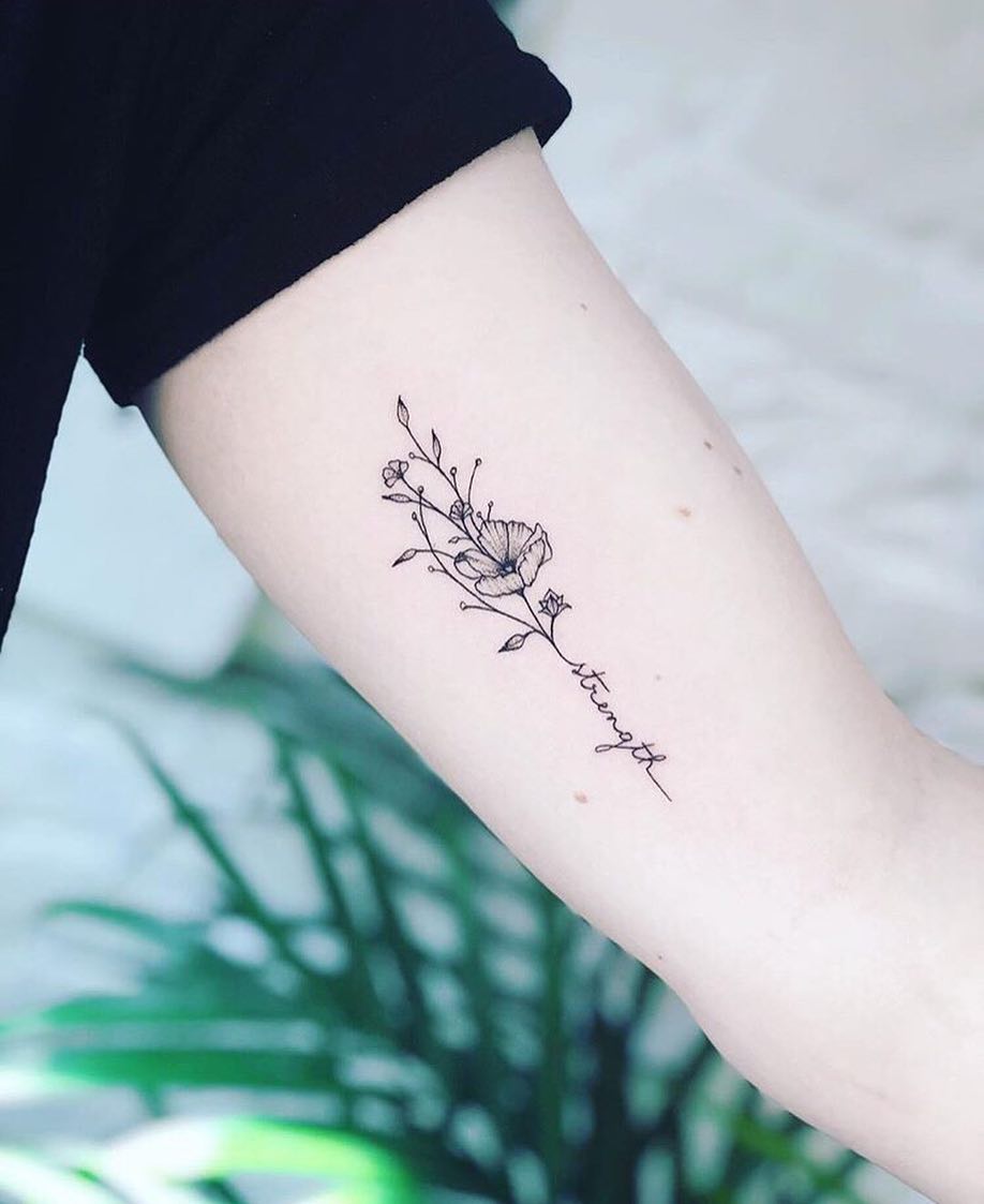 Elegant floral strength tattoo on the arm