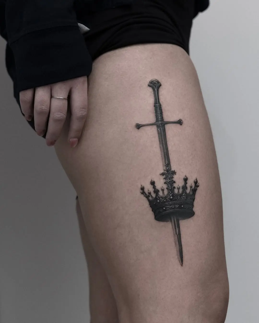 Bold sword and crown tattoo design