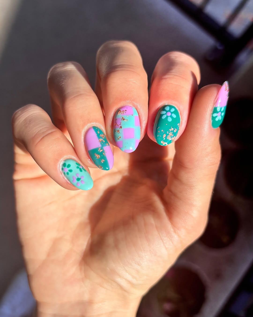 Vibrant teal nails with playful designs and patterns