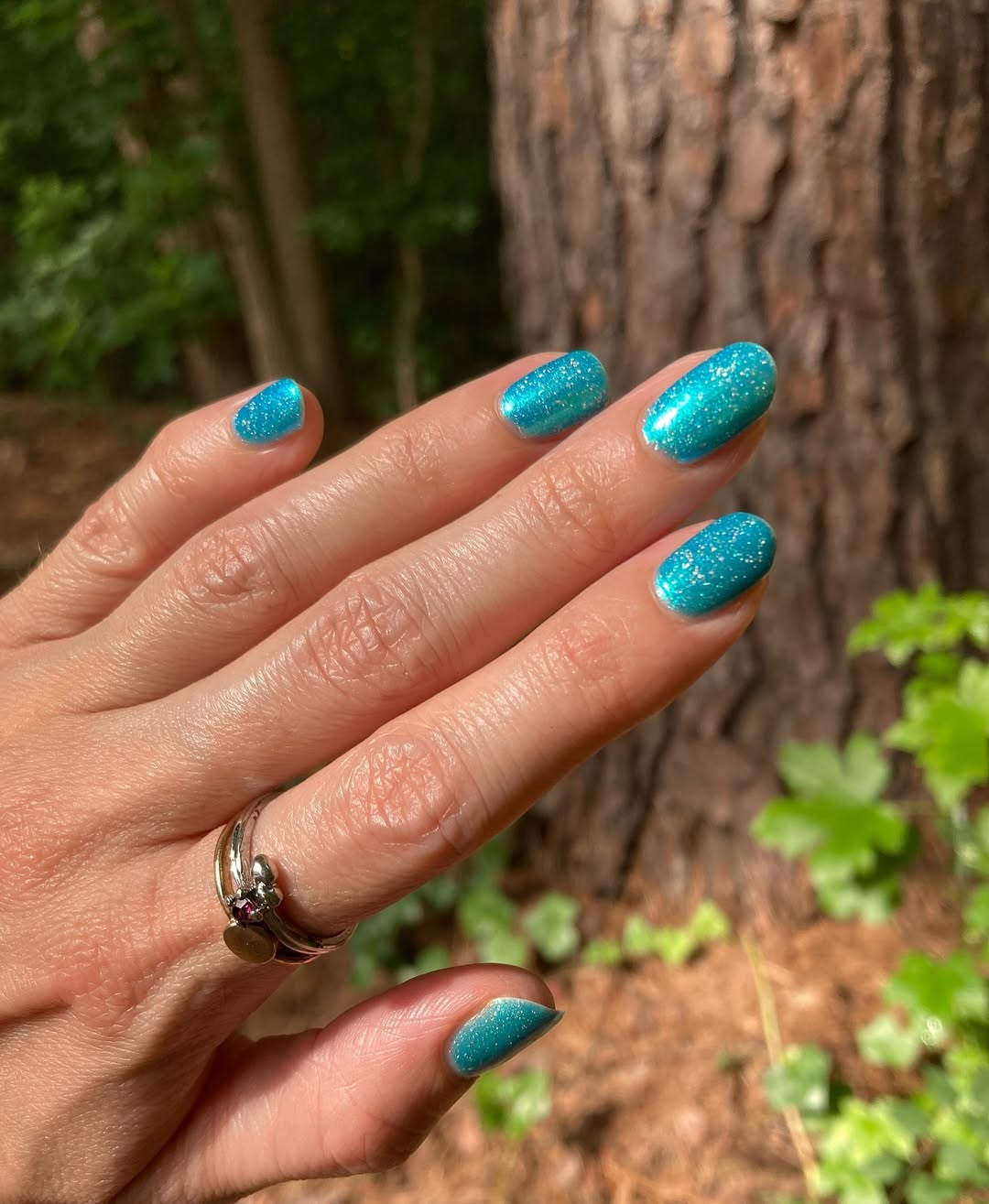Vibrant teal nails with sparkle accent