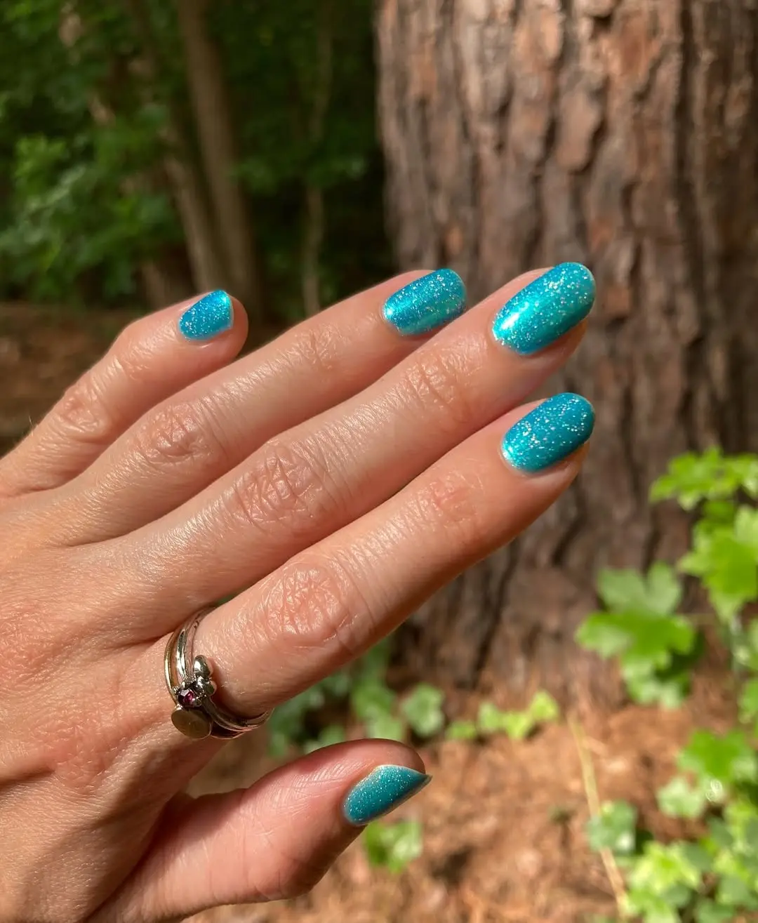 Vibrant teal nails with sparkle accent